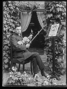97 Portret van een man met viool op stoel poserend met muziekboek van Wagner, ca 1905-1935