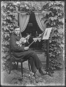 98 Portret van man met viool op stoel poserend met muziekboek, ca 1905-1935